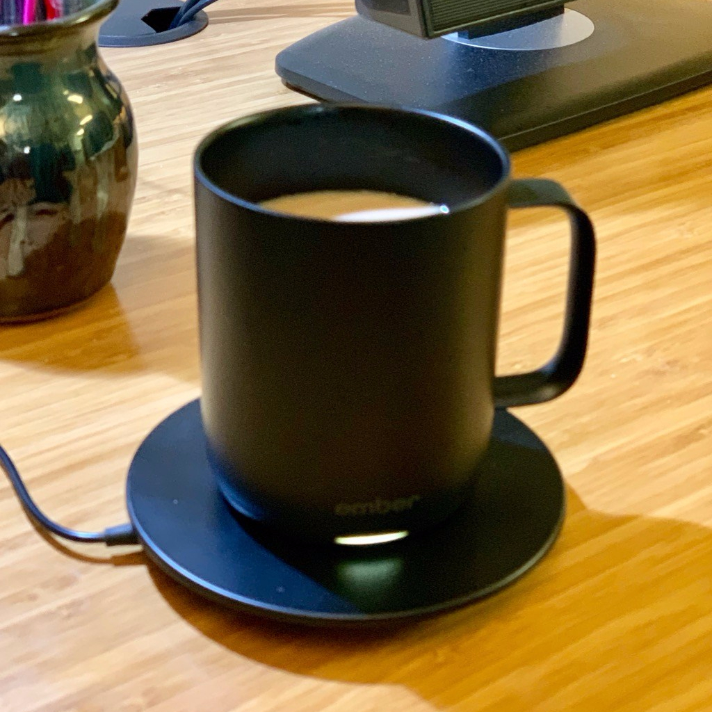 Ember Mug sitting on charging coaster on a desk.